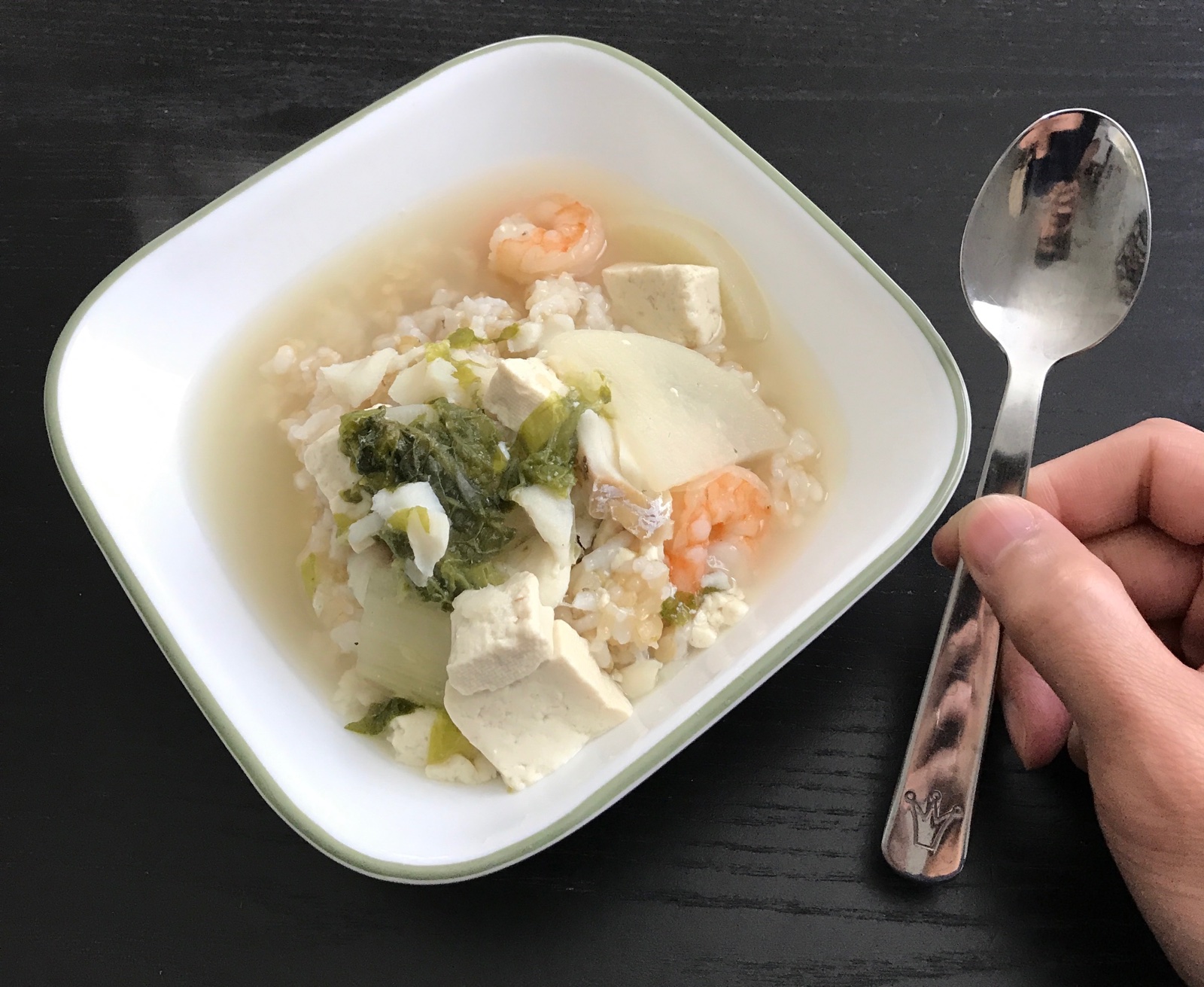 Bowl of soup with a hand holding a kid's spoon